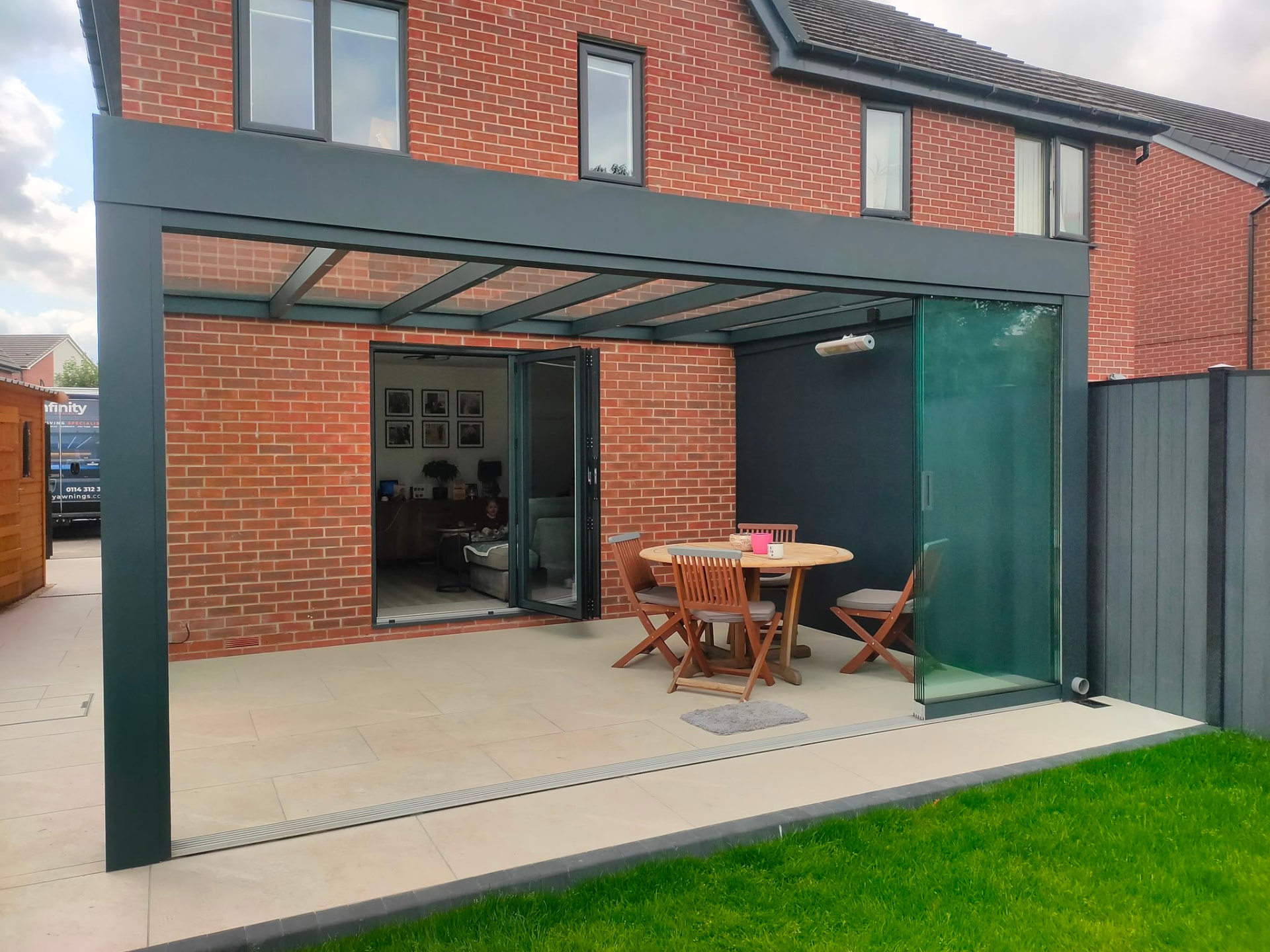 Glass room with a glass roof and sliding glass side beside bifold doors