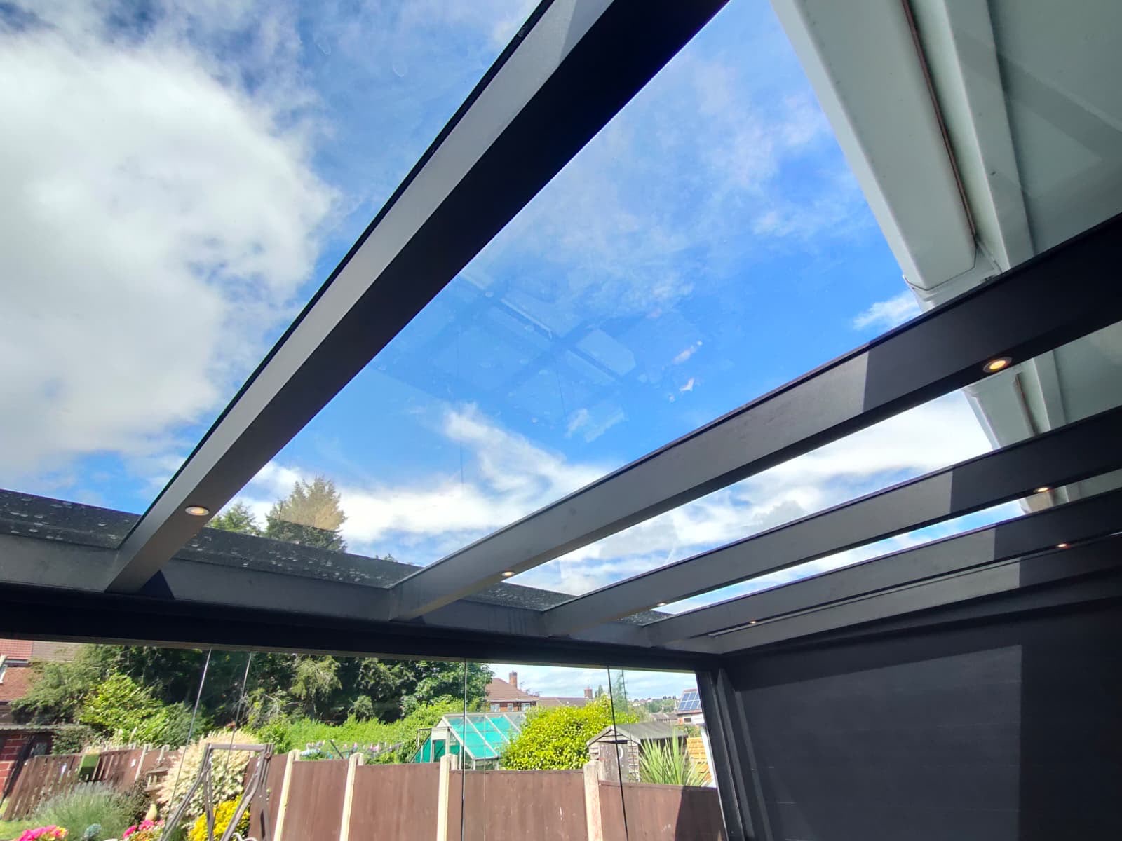 Underside of a glass veranda roof showing rafters and integrated LED spotlights
