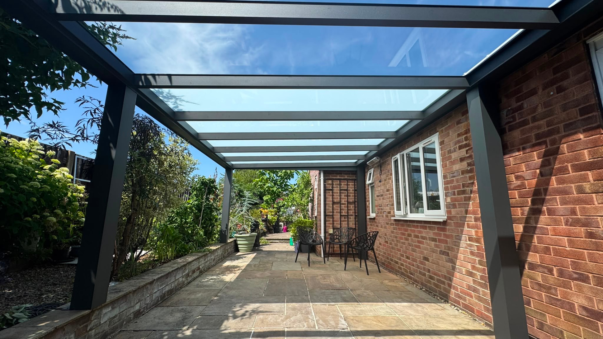 Glass roof veranda running along a red brick bungalow patio
