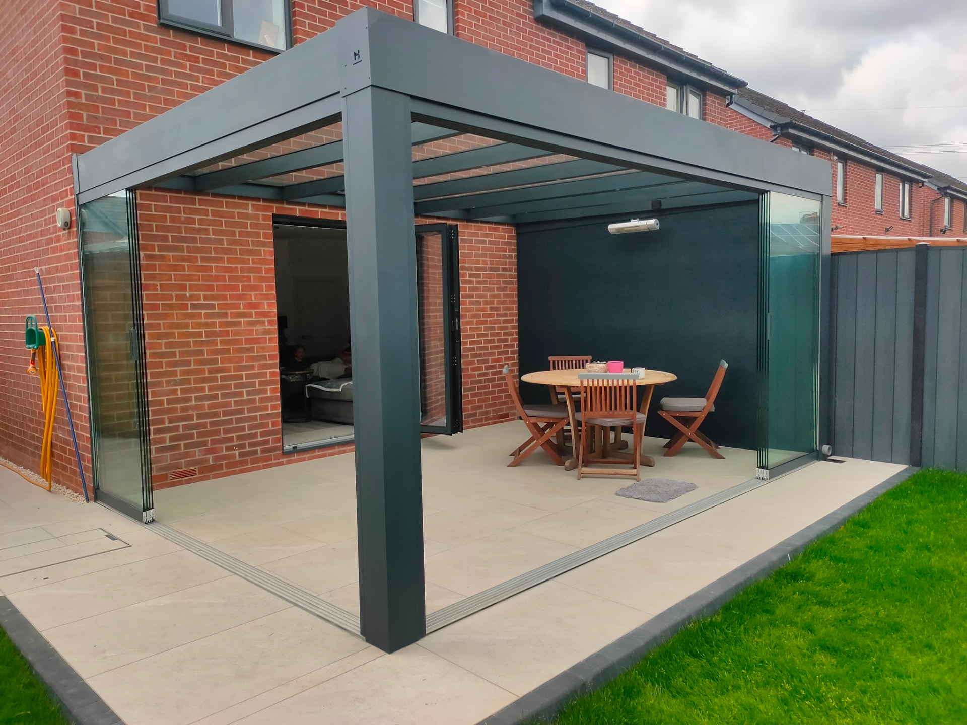 Corner view of an anthracite glass room with glass roof and sliding sides