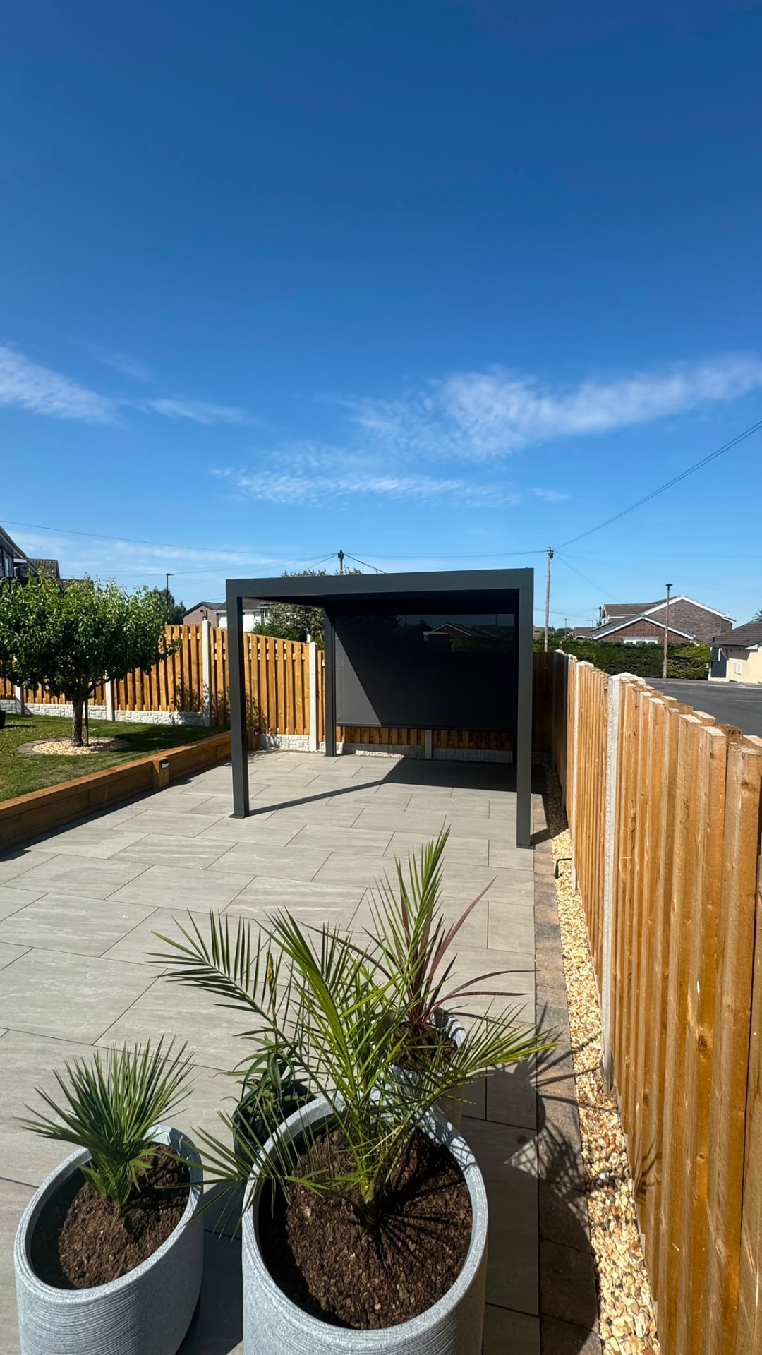 Freestanding aluminium pergola with a zip screen on a porcelain patio