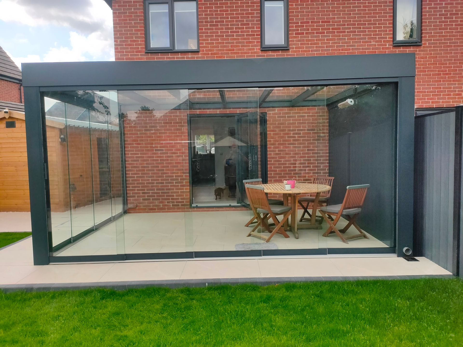 Glass room with full height sliding glass walls and a garden dining set