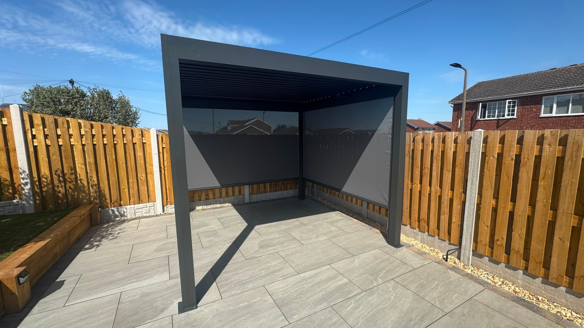 Freestanding louvered pergola with zip screens on a grey patio