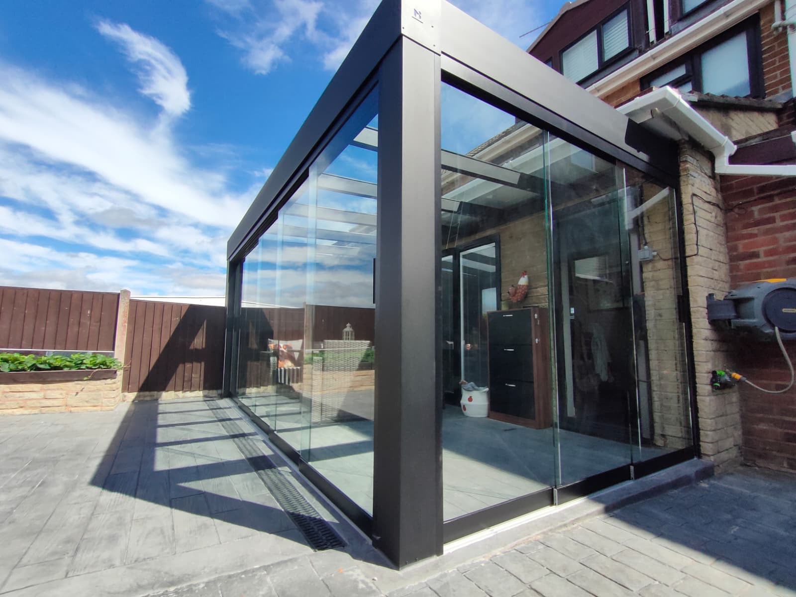 Corner view of a glass veranda with glass roof and sliding sides